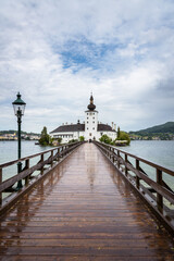 Obraz premium Sky begins to open after the storm over Seeschloss Ort castle located on a small island on Traunsee lake, Gmuden, Austria