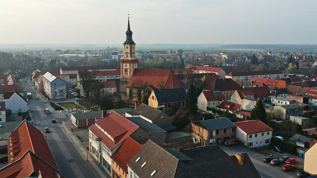 Aerial views flying over Templin, a small town in Germany in the federal state of Brandenburg, in winter.  You can see the street with cars and a bus and the church next to many old buildings.