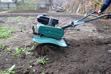 A man cultivates a garden with a cultivator.