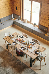 High angle view of dining table decorated with autumn branches and beautiful service standing in big dining room