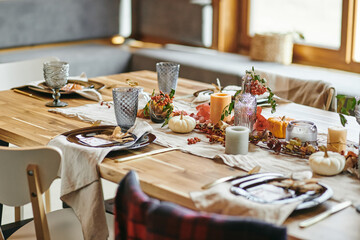 Close-up of beautiful autumn decoration from candles vegetables and branches on dining table