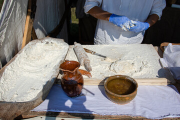 Traditional cooking utensils, flour in a wooden tub. Male hands prepare a dish of flour