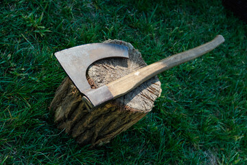 An ax with a long hatchet and a long blade, reminiscent of an ancient executioner's ax. Ax on a pine stump
