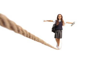 Schoolgirl in a uniform holding a book and walking on a rope