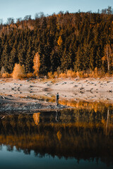 A outdoor adventure man exploring a wild mountain lake. Colorful autumn wilderness on a sunny hiking outdoor day. Harz Mountain, Harz National Park, Germany
