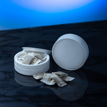 Closeup of a white swedish snus can and portion snuff pouches.