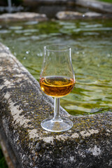 Glass of strong scotch single malt whisky served on old stone reservoir for water from mountain spring