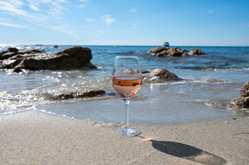 Summer time in Provence, glass of cold rose wine on sandy beach and blue sea near Saint-Tropez, Var department, France