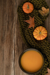 bowl of pumpkin soup on the wooden table decorated with winter squash and autumn leaves