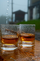 Glasses of strong scotch single malt whisky and rain water drops