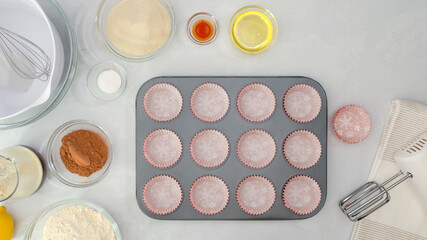Muffin pan with paper cupcake liners, and ingredients for chocolate muffin recipe close up on kitchen table