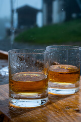Glasses of strong scotch single malt whisky and rain water drops