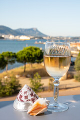Summer on French Riviera, drinking of cold white or gris rose wine from Cotes de Provence on outdoor terrase with view on harbour of Toulon, Var, France and sea shells