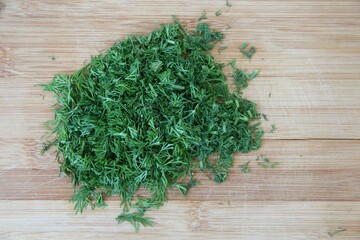 Chopped dill on the wooden cutting board, close-up