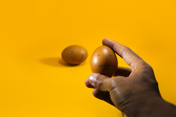 Conceptual Illustration for questionnaire, feedback rating, customer review, experience, and satisfaction survey. Hand choosing sad face brown egg on orange background.