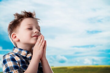little child praying to God with hands together and a smile