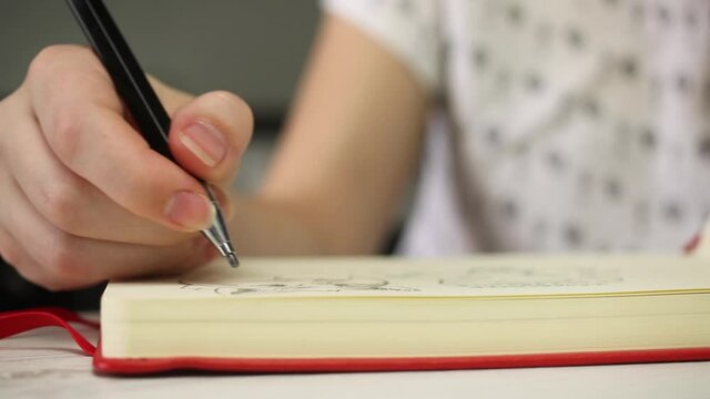 Close-up view of woman hands drawing on white paper of art book notebook with pencil. Art creation, creativity, education and learing lessons concept
