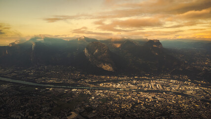 Grenoble aerial view of the valley with the famous city of France surrounded by french alps mountains during epic cloudy sunset 