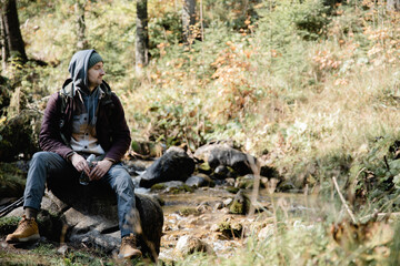 Fototapeta premium Male hiker is traveling at the mountains with backpacks exploring beautiful places of the natural park enjoying the outstanding landscape views.