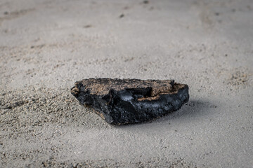 A piece of natural asphalt on a gray plaster background