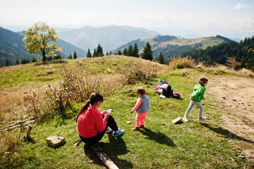 Fototapeta premium Mother with daughters enjoying in the mountains.The concept of family travel, adventure, and tourism. Lifestyle and hiking autumn vacations outdoor.