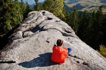 Boy on top of mountain. Children hiking on beautiful day in mountains, resting on rock and admire...