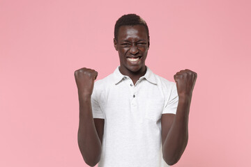 Joyful young african american man guy in white polo shirt posing isolated on pastel pink wall...