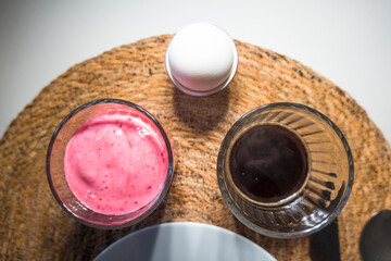 A breakfast of smoothie, coffee and hard boiled egg.