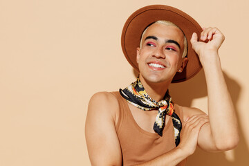 Young pensive minded fun smiling happy blond latin gay man 20s with make up in beige tank shirt...