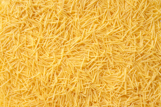 Delicious noodles texture. Healthy food and eating concept. Textured background with yellow pasta. Macaroni for soup. Uncooked Italian vermicelli. High-quality photo closeup