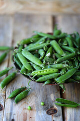 Fresh green peas in a peel on a wooden surface.