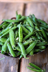 Fresh green peas in a peel on a wooden surface.