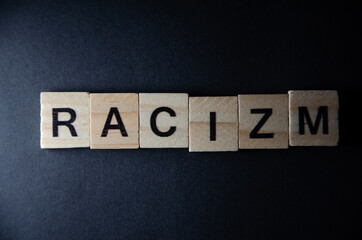 Inscription Racism outlined on dark background with copy space. Selective focus on Lettering Racism. Banner on black background. Concept of inequality of nations.