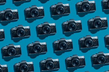 Pattern of old rustic vintage film cameras on blue