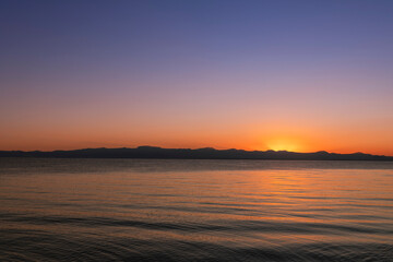 
Beautiful bright sunset sky on the lake and silhouette mountains on the horizon.