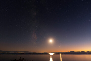 Night landscape, milky way galaxy and moon above the lake.
