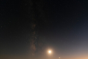 Beautiful bright milky way galaxy with long exposure cloud on the blue starry sky  and moon. Space, astronomical background. Cosmos wallpaper.