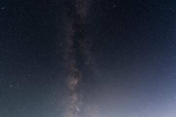 Beautiful bright milky way galaxy with long exposhure cloud on the blue starry sky. Space, astronomical background.