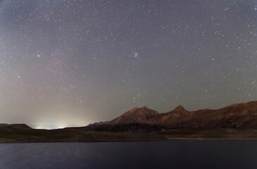 Beautiful night landscape. Small lake and mountains under starry sky.