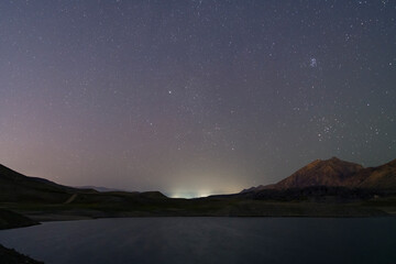 Beautiful night landscape. Small lake and mountains under starry sky.