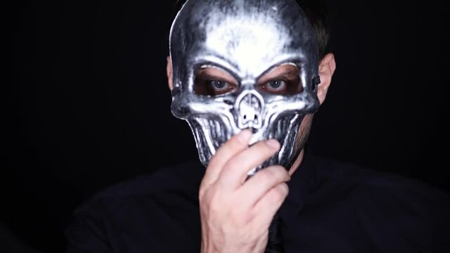 a man puts a skeleton mask on his face and holds it