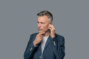 Serious pensive man with smartphone near ear