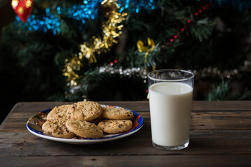 Cookies and a glass of milk on a Christmas tree background.