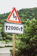 Road sign indicating a dangerous turn - road in the mountains