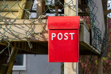 Red metal mail box with white letters outside residential house