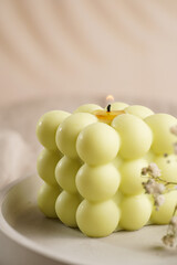 One white square bubble candle on a concrete tray on a linen table cloth with a blooming branch