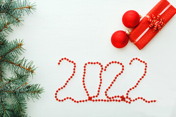 2022 lettering Happy New year Christmas composition card with presents gift boxes on white wooden table. Festive greeting card red Garlands in shape of 2022 numbers. Flat lay