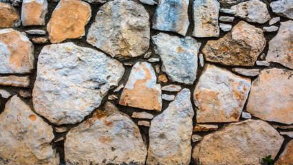 Stone antique old wall as a background or texture. Vintage background of a fortress wall in loft and grunge style with place for text and copy space.
