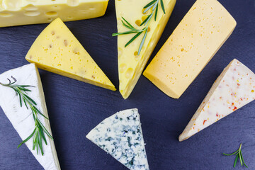 Set of various types of cheese on black slate background. Top view