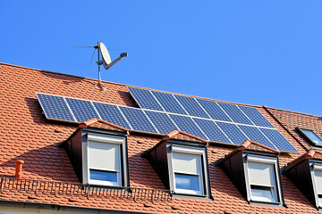 Photovoltaikanlage auf rotem Hausdach, mit SAT-Antenne
